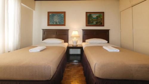 - 2 lits dans une chambre avec une lampe sur une table dans l'établissement El Rico Suite Makati by RedDoorz, à Manille