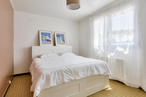 una camera bianca con un letto e una finestra di Parenthese entre plage et foret a La Barre-de-Monts
