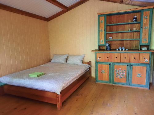 1 dormitorio con 1 cama y armario de madera en Wood Cabins in the heart of Transylvania en Colţeşti