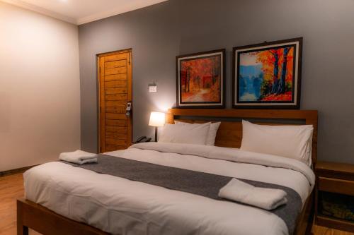 a bedroom with two beds and two paintings on the wall at Dynasty Hotel Skardu in Skardu
