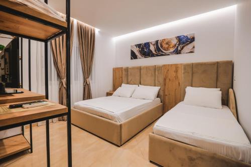 two beds in a room with a desk and a bed at Vila Ahmeti in Sarandë