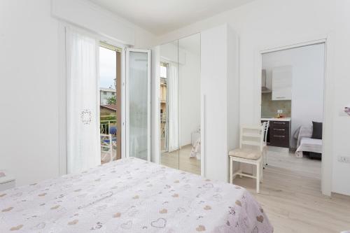 een witte slaapkamer met een bed en een stoel bij Villa Graziano in Cesenatico