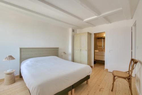 een witte slaapkamer met een bed en een stoel bij Escale apaisante au port de Saint-Martin-de Re in Saint-Martin-de-Ré