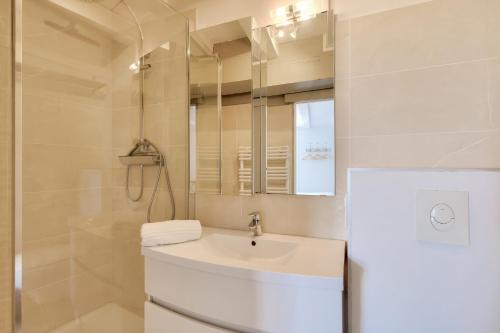 een witte badkamer met een wastafel en een spiegel bij Escale apaisante au port de Saint-Martin-de Re in Saint-Martin-de-Ré