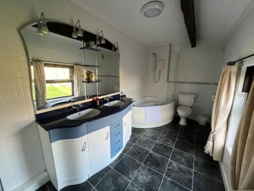 y baño con 2 lavabos, bañera y aseo. en Rural Family Farmhouse with Countryside views en Southport