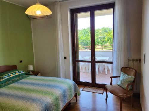 - une chambre avec un lit, une fenêtre et une chaise dans l'établissement COLLINA FIORITA, à Tollo