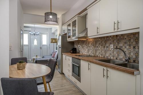 a kitchen with white cabinets and a table and a sink at Suites 33 in Kos Town