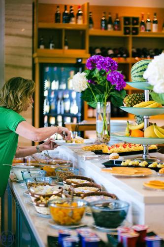 a woman is preparing food at a buffet at Hotel Saranda Butrinti, Affiliated by Melia in Sarandë