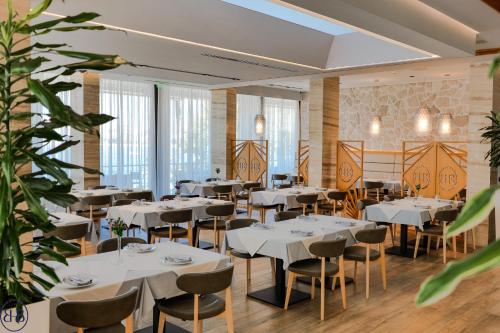 Hotel Butrinti & SPA في سارنده: مطعم بطاولات بيضاء وكراسي ونباتات