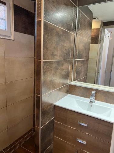 une salle de bain avec un lavabo et un miroir dans l'établissement Appartement Liberssan les pieds dans le sable, rez de plage, à Gruissan