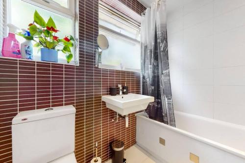 a bathroom with a sink and a toilet and a window at Modernistic 2 BR maisonette in Kingsbury in Colindale
