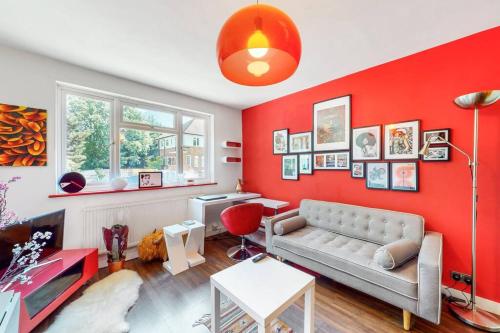 a living room with a couch and a red wall at Modernistic 2 BR maisonette in Kingsbury in Colindale
