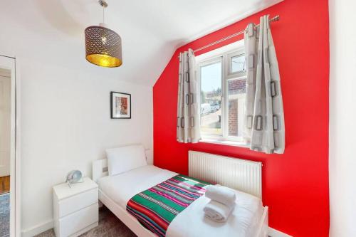 a red bedroom with a white bed and a window at Modernistic 2 BR maisonette in Kingsbury in Colindale