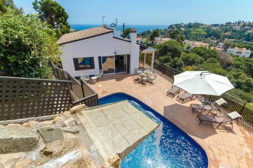 a house with a swimming pool and an umbrella at Villa Luxury piscina y cascada 2 min de la playa in Lloret de Mar
