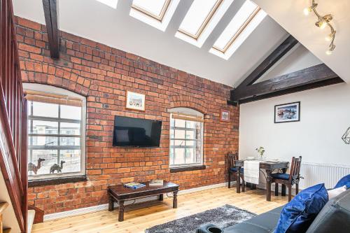 a living room with a brick wall and a tv at Beautiful 1-Bed Apartment in Grade Listed Warehouse - Victoria Quays, Sheffield City Centre, FREE Parking, Pet Friendly, Netflix in Sheffield