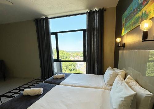 N1 Hotel Samora Machel Harare في هراري: غرفة نوم بسريرين ونافذة كبيرة