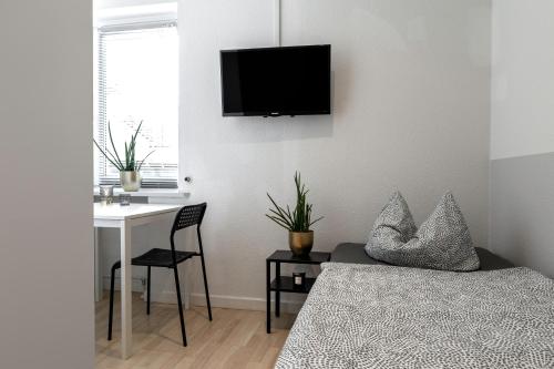 a bedroom with a bed and a desk and a tv on the wall at Haus KÖ 17 in Norderstedt