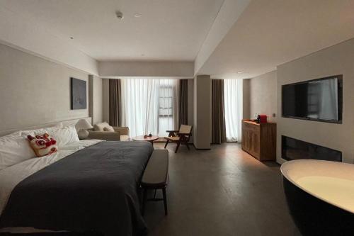 1 dormitorio con 1 cama grande y sala de estar en Phoenix Hall House Hotel, en Fenghuang