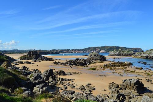 a beach with rocks in the sand and water at Apartamento El Olivo in Noja