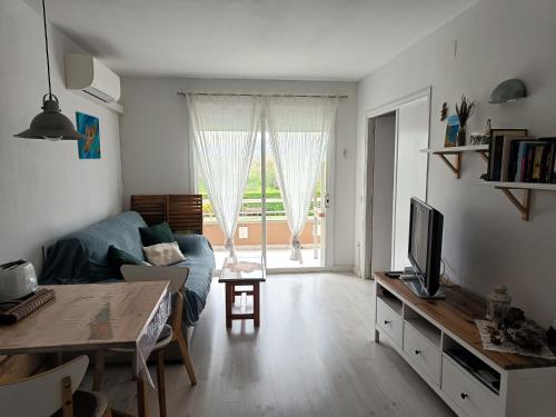 uma sala de estar com um sofá azul e uma televisão em Cozy apartment with pool close to beach & nature em L'Estartit