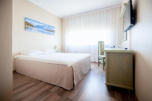 a bedroom with a large white bed and a television at Hotel Dzingel in Tallinn