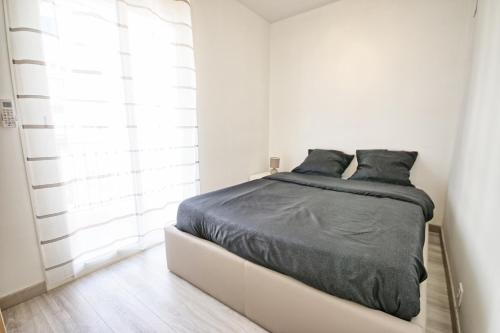 - une chambre blanche dotée d'un lit avec des draps noirs dans l'établissement Résidence Gambetta, à Antibes