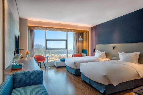 a hotel room with two beds and a large window at Holiday Inn Express Taian City Center, an IHG Hotel in Tai'an