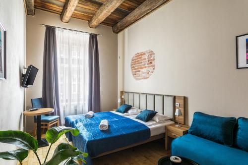 1 dormitorio con 1 cama azul y 1 sofá en Aparthotel Pergamin, en Cracovia