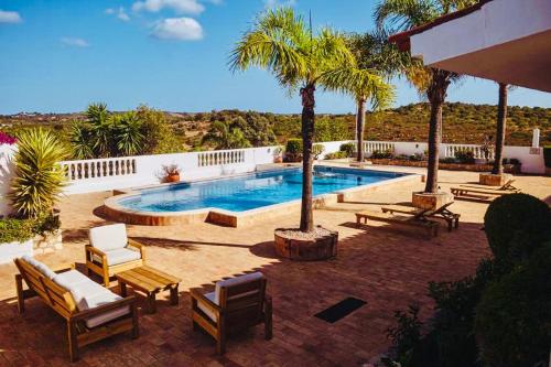 - une piscine avec des chaises et un palmier dans l'établissement Quinta da Bela Vista, à Lagos