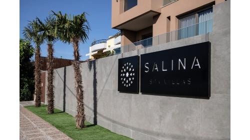 a sign on the side of a building with palm trees at Salina SPA Villas - with PRIVATE HEATED ECO-POOL, SAUNA & JACCUZI HOT TUB in Volos