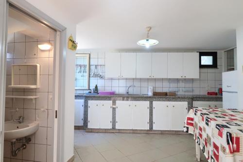 a kitchen with white cabinets and a sink and a table at Trullo - Cantoru in Marina di Pescoluse