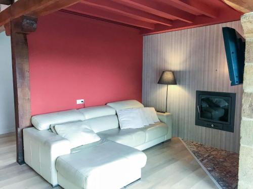 a living room with a couch and a red wall at Cantabria Collection - Espectacular casa con piscina y jardín in Oruña