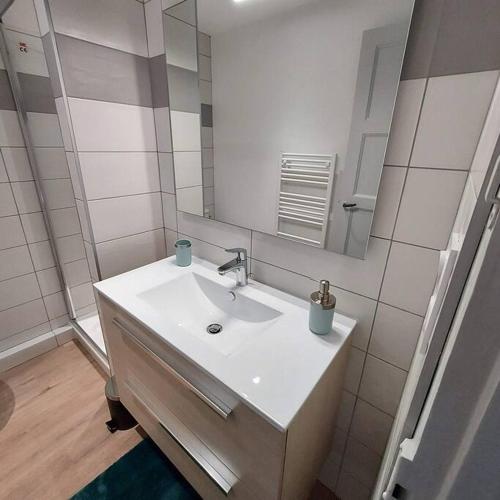 a white bathroom with a sink and a mirror at Appartemement F2 refait à neuf hyper centre in Coutances