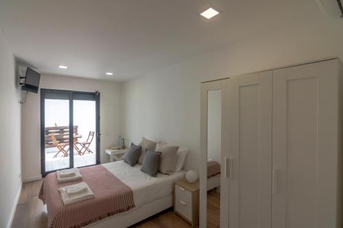 a white bedroom with a bed and a window at Beach & Sea Guesthouse in Espinho