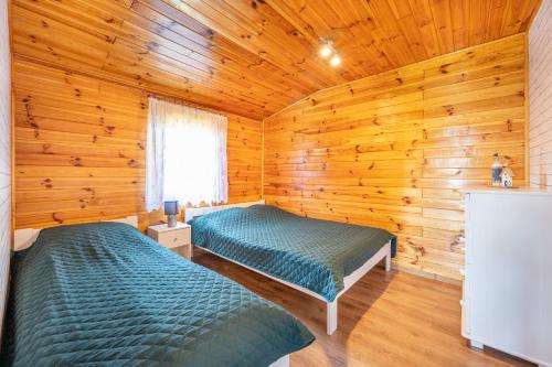 a bedroom with two beds in a wooden cabin at Uroczy Zakatek in Chłopy