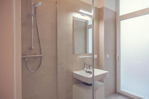 ein Bad mit einer Dusche, einem Waschbecken und einem Spiegel in der Unterkunft The 77 ALMA in Wien