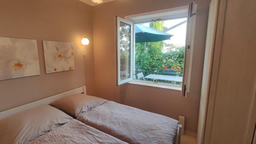 a bedroom with a bed and a window with an umbrella at Apartments Ruzic Njivice in Njivice
