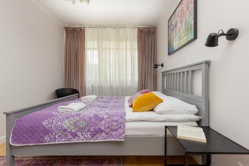 1 dormitorio con cama morada y mesa en Wincentego Park Apartment by Renters en Varsovia