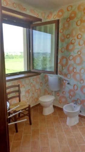 a bathroom with two toilets and a window and a sink at il Balcone sul Monferrato in Tonco