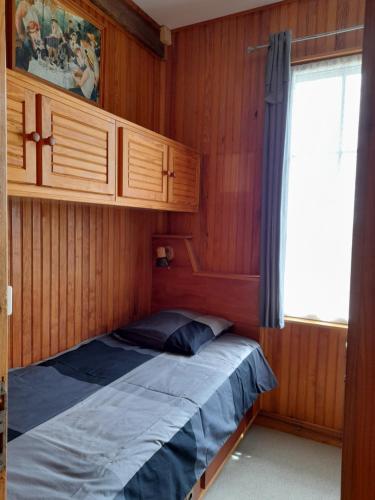 Ce lit se trouve dans un dortoir doté de murs en bois et d'une fenêtre. dans l'établissement Gite Ancien Lavoir, à Viserny