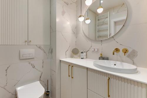 a white bathroom with a sink and a mirror at Grano Residence Riverview - Pool, Gym & SPA by Downtown Apartments in Gdańsk