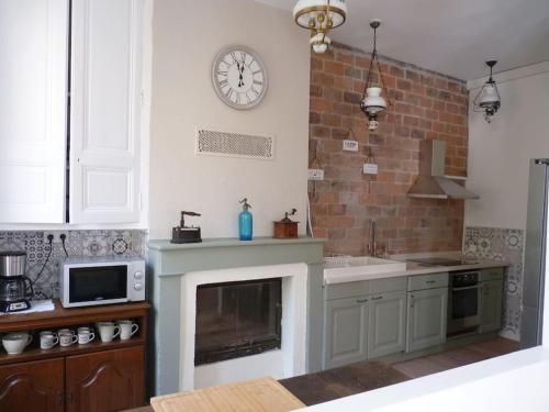 a kitchen with a fireplace and a clock on the wall at Des Envies et Des Songes in Saint-Amand-en-Puisaye
