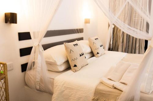 Schlafzimmer mit einem Bett mit weißen Vorhängen in der Unterkunft Beautiful Beachfront Villa - Lumi Villa in Tangalle