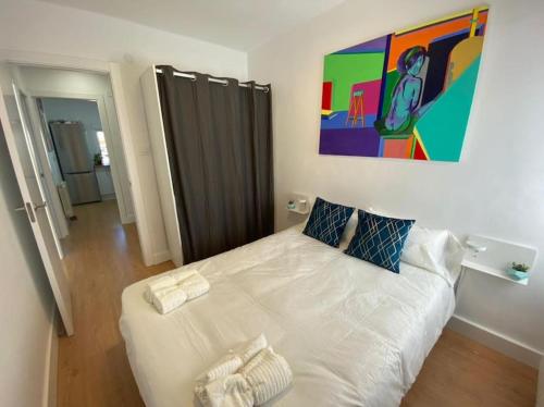 1 dormitorio con 1 cama blanca y una pintura en la pared en Apartamento Céntrico-parking gratis Julio y Agosto-Wifi en Santander