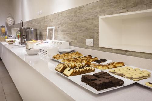 Un mostrador con varios tipos diferentes de pasteles y tartas. en Facón Del Mar Hotel, en Mar del Plata