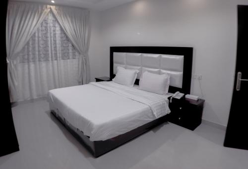 ein Schlafzimmer mit einem großen Bett mit weißer Bettwäsche und Kissen in der Unterkunft روز للشقق الفندقية in Hotat bani tamim