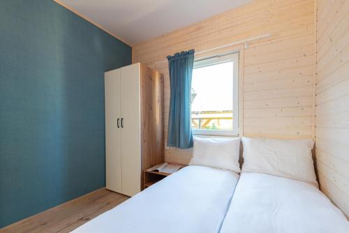 a bedroom with a large bed with a window at MIELENKO BEACH - domki in Mielenko
