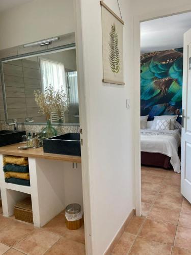 une salle de bain avec un lavabo et une chambre avec un lit dans l'établissement Les Jardins d'Holi proche Uzès, à Garrigues-et-Sainte-Eulalie