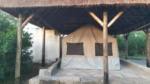 a tent that is under a straw roof at Engiri Game Lodge and Campsite in Katunguru