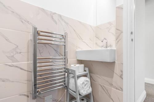 a bathroom with white marble walls and a sink at Surrey Street Duplex in Norwich